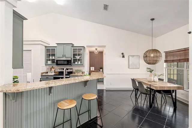 a kitchen with stainless steel appliances a dining table chairs and white cabinets