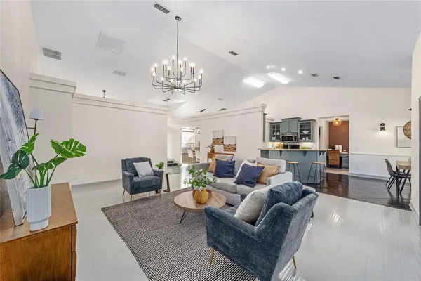 a living room with furniture kitchen view and a chandelier