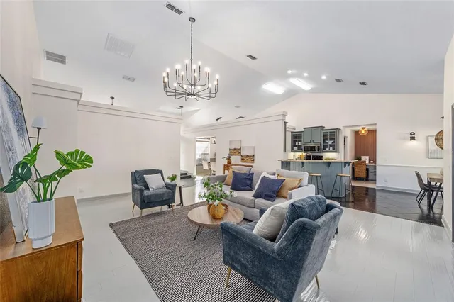 a living room with furniture kitchen view and a chandelier