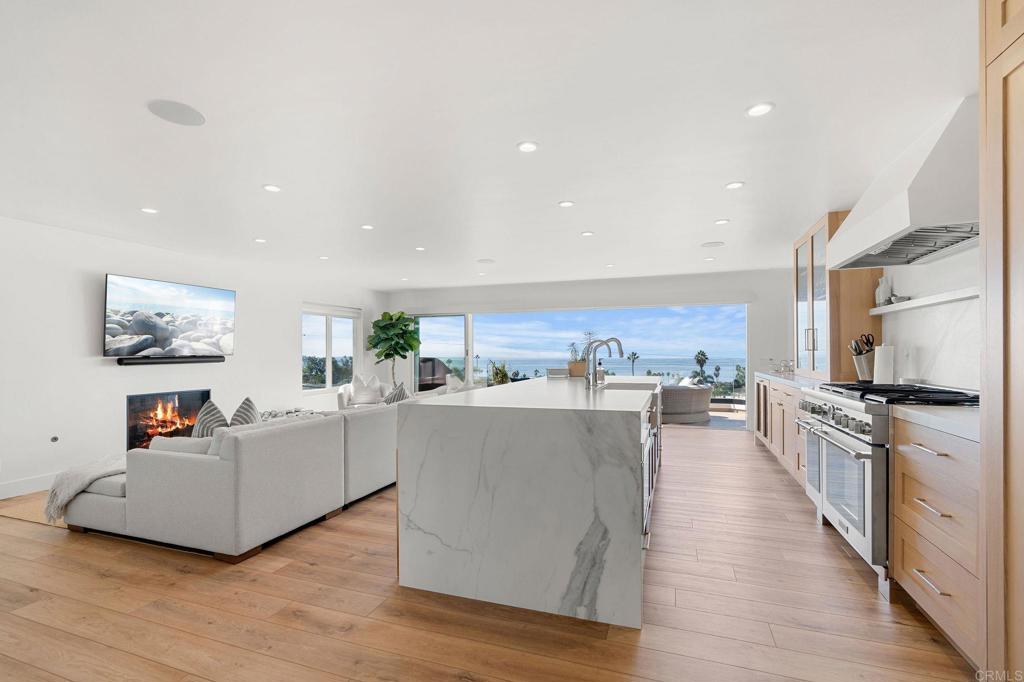 a living room with stainless steel appliances furniture and a kitchen view