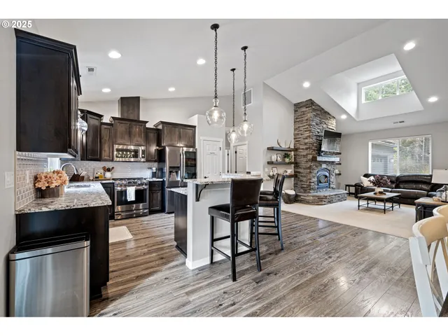 a open kitchen view with stainless steel appliances kitchen island granite countertop a table chairs and a refrigerator