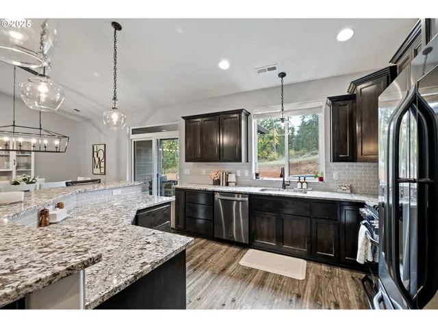 a kitchen with stainless steel appliances kitchen island granite countertop a sink stove and refrigerator