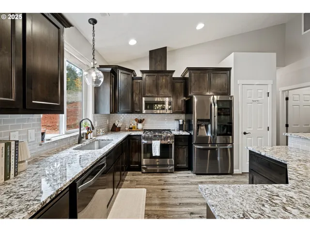 a kitchen with stainless steel appliances granite countertop a sink a stove and a refrigerator
