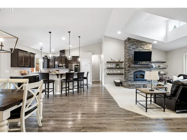 a living room with stainless steel appliances furniture a fireplace a flat screen tv and view