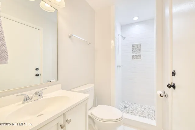 a bathroom with a sink a toilet a mirror and shower