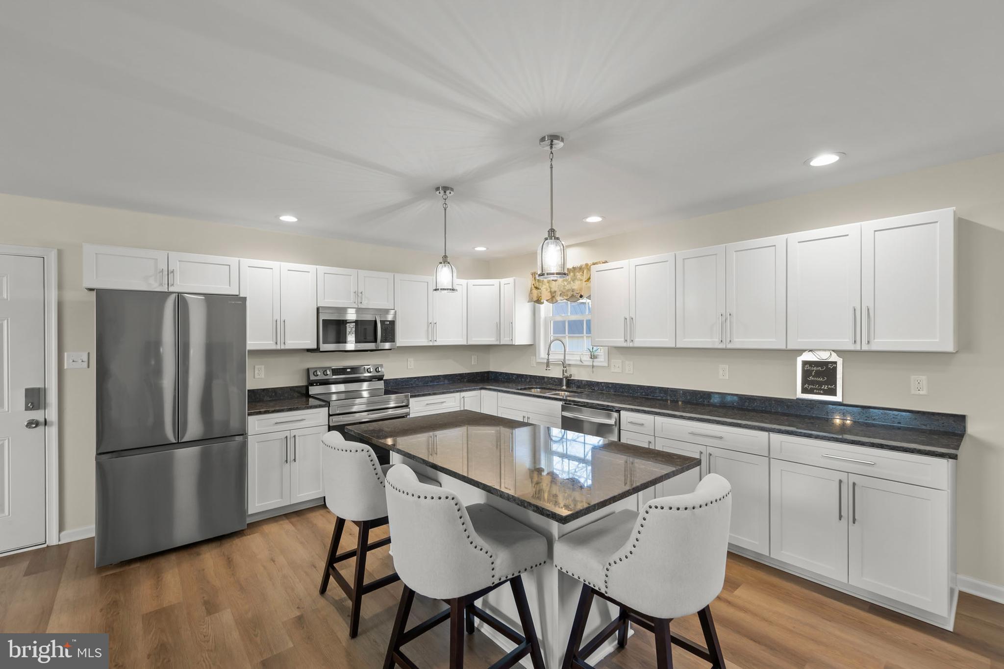 4009 Ridge Road Quicksburg, VA 22847 - Photo 3 of 41 a kitchen with stainless steel appliances granite countertop a sink a stove a refrigerator and white cabinets with wooden floor