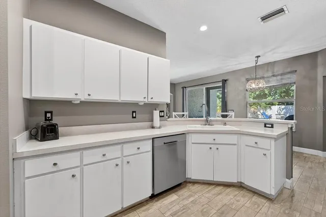 a kitchen with stainless steel appliances kitchen island granite countertop a dining table chairs refrigerator and sink