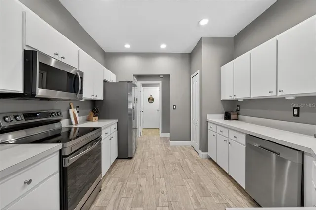 a kitchen with kitchen island stainless steel appliances a dining table chairs sink and cabinets