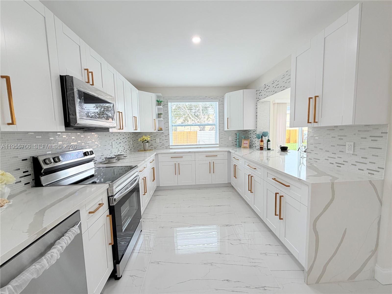 4241 Thomas Street Hollywood, FL 33021 - Photo 33 of 91 a large white kitchen with stainless steel appliances granite countertop a stove a sink dishwasher and a refrigerator