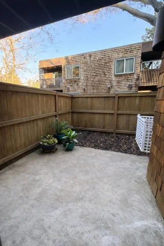 a view of a backyard with plants and brick wall