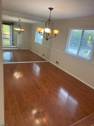 a view of a room with wooden floor and chandelier