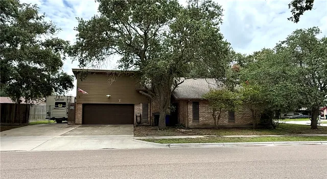 a front view of a house with a garden and trees