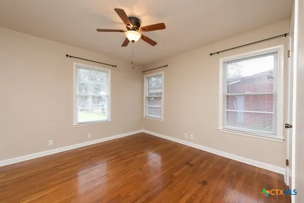 a view of an empty room with wooden floor and a window