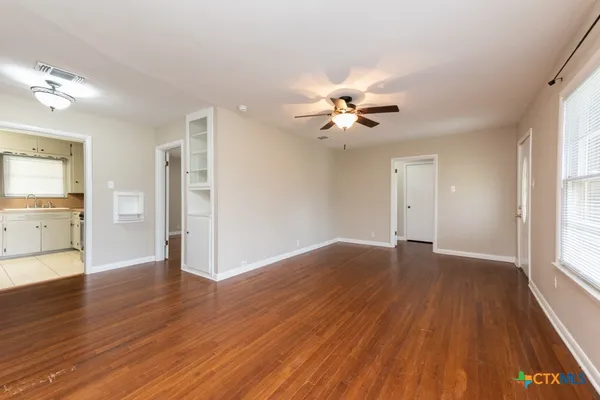 a view of an empty room with a window and wooden floor