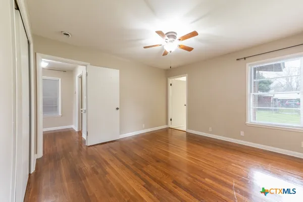 a view of an empty room with wooden floor and a window