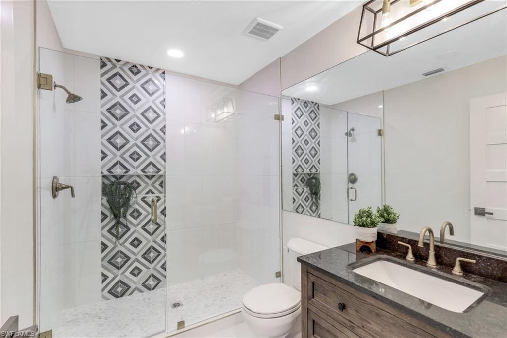 651 Bridge Way Lane, Unit 143 Naples, FL 34108 - Photo 17 of 27 a bathroom with a granite countertop sink a toilet a mirror a vanity and shower