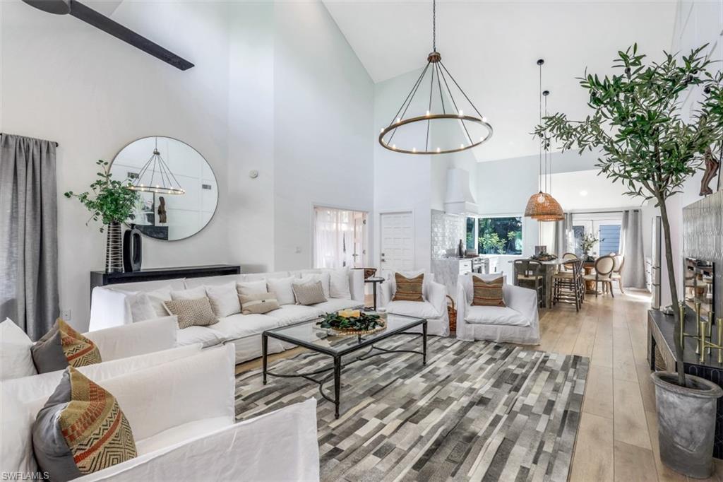 651 Bridge Way Lane, Unit 143 Naples, FL 34108 - Photo 5 of 27 a living room with furniture a dining table and a chandelier