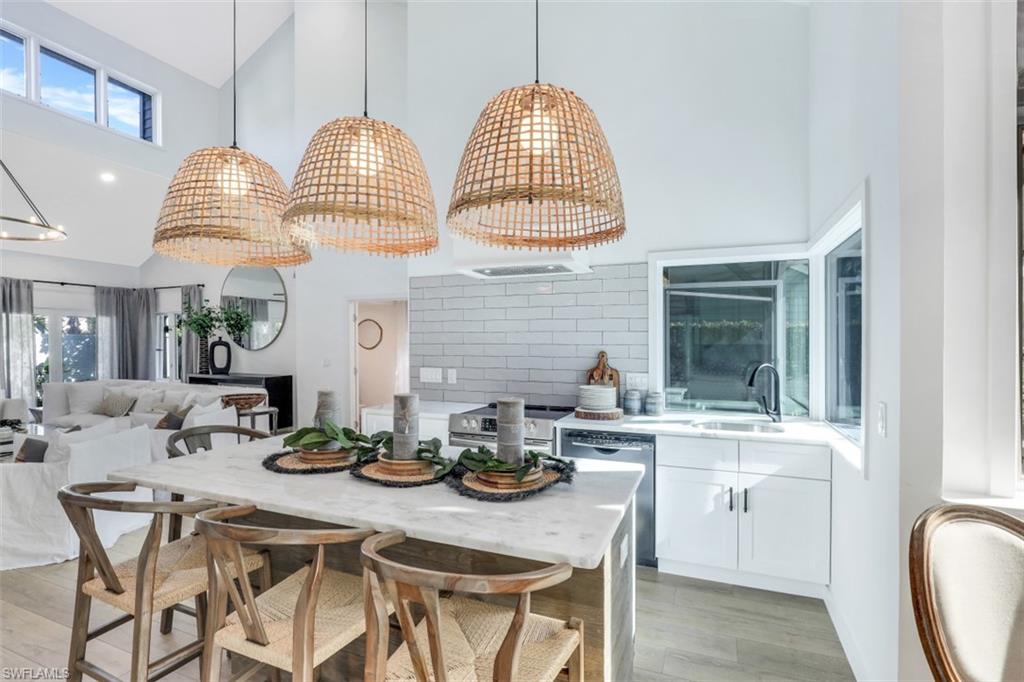 651 Bridge Way Lane, Unit 143 Naples, FL 34108 - Photo 7 of 27 a kitchen with stainless steel appliances granite countertop a sink dishwasher a dining table and chairs with wooden floor