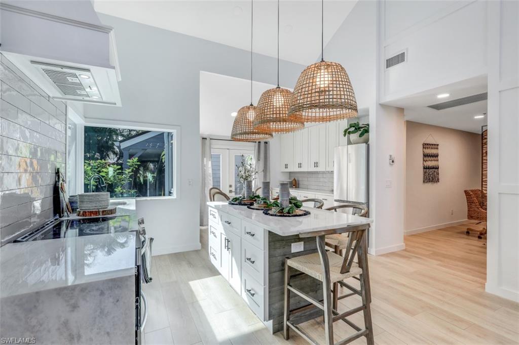 651 Bridge Way Lane, Unit 143 Naples, FL 34108 - Photo 8 of 27 a dining room with wooden floor a chandelier a wooden table and chairs