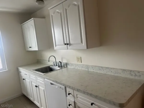 a kitchen with granite countertop a sink and a white cabinets