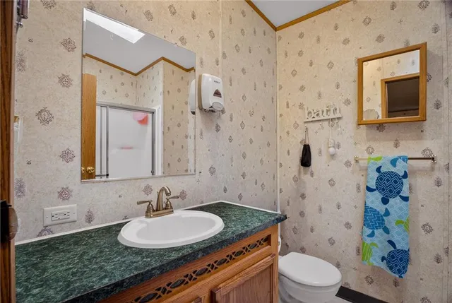 a bathroom with a granite countertop sink a toilet a mirror and shower curtain