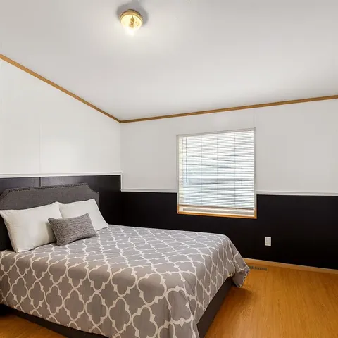 a bedroom with a bed and a lamp on dresser