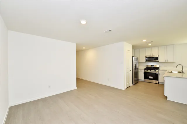 a view of a kitchen with a sink and dishwasher a refrigerator with white cabinets