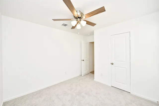 an empty room with a ceiling fan and a window