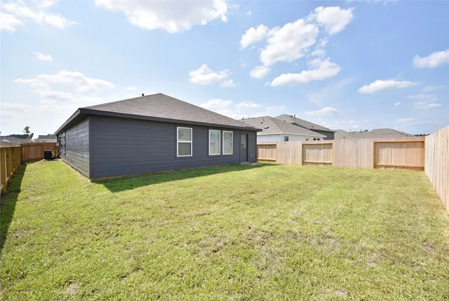 a brick house next to a yard with wooden fence