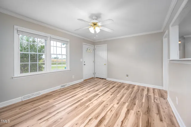 a view of an empty room with wooden floor and a window