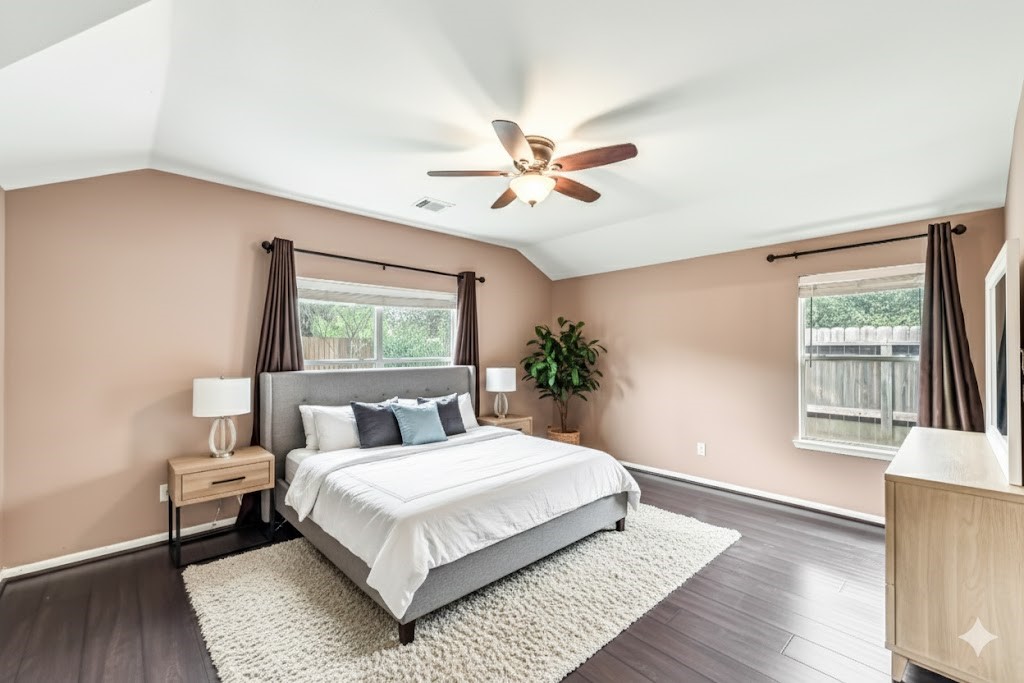 1602 Rustic Hollow Lane Katy, TX 77450 - Photo 21 of 48 pacious primary bedroom featuring large windows for excellent natural light, vaulted ceiling with ceiling fan, and rich wood-look flooring. Offers ample space for a king-size bed and additional furniture, creating a comfortable and inviting retreat.