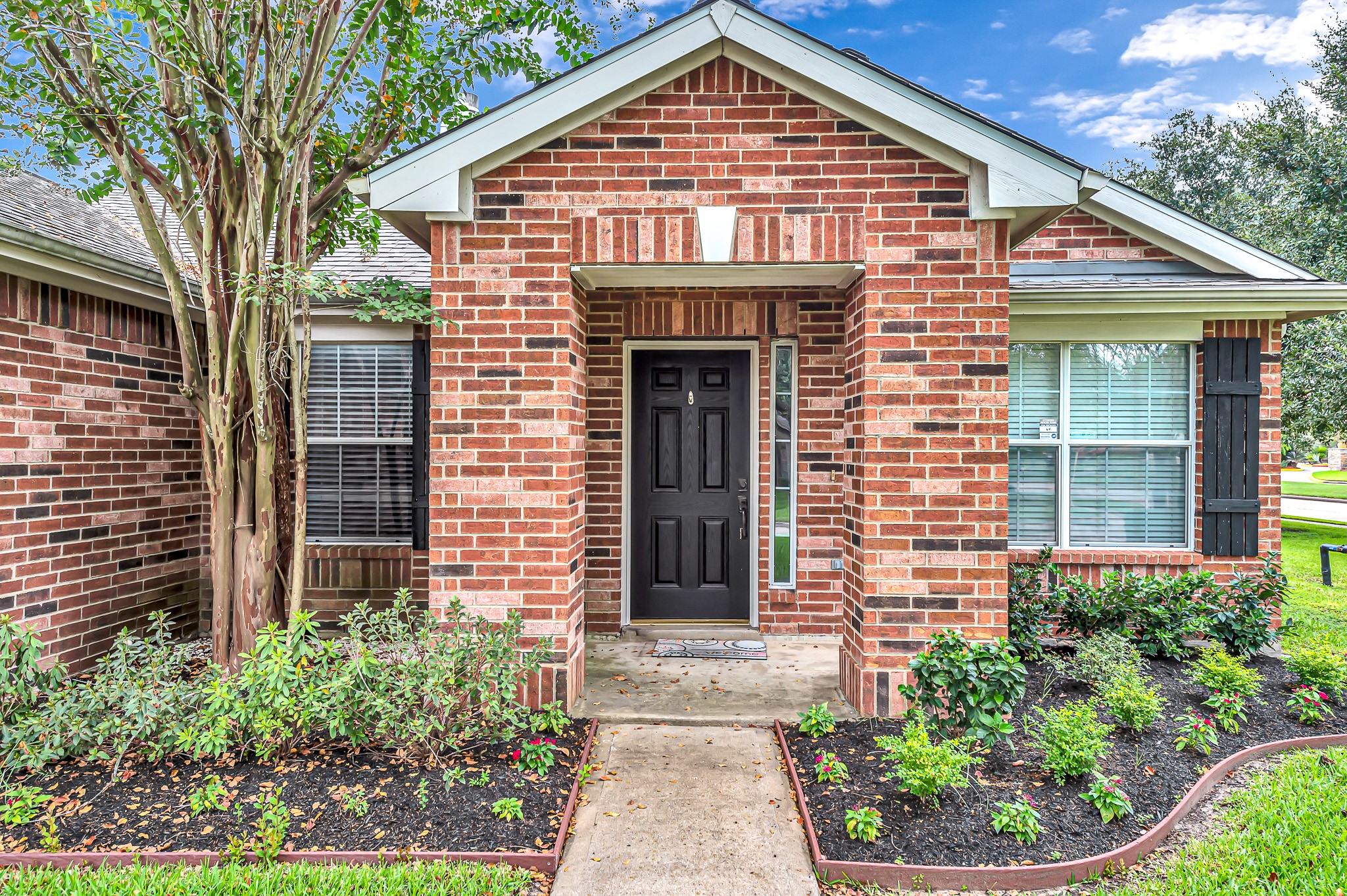 1602 Rustic Hollow Lane Katy, TX 77450 - Photo 5 of 48 Inviting covered entry with a classic brick façade, fresh landscaping, and a stylish front door. A welcoming walkway leads to the porch, creating great first impressions.