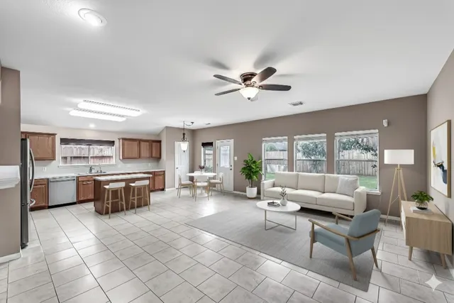 a living room with furniture a large window and kitchen view