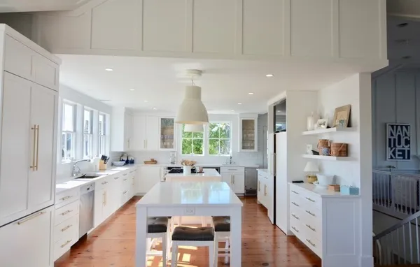 a large white kitchen with stainless steel appliances granite countertop a lot of counter space and wooden floors