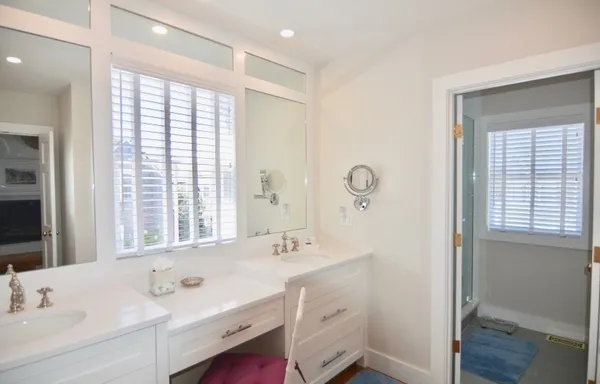 a bathroom with a double vanity sink mirror and next to a window