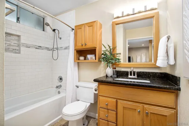 a bathroom with a granite countertop sink toilet mirror and a bathtub