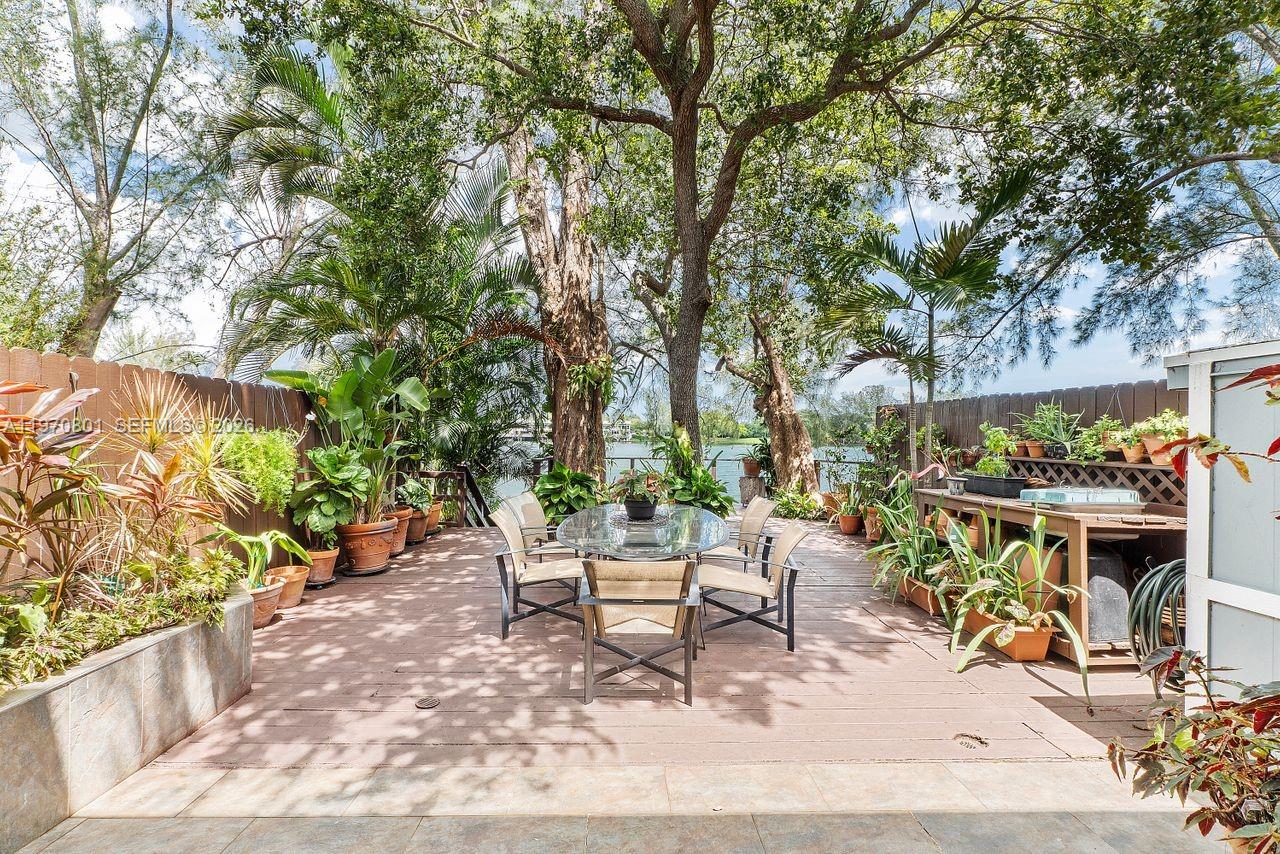 4905 Southwest 71st Place Miami, FL 33155 - Photo 25 of 37 a view of a patio with table and chairs and potted plants with wooden floor and fence