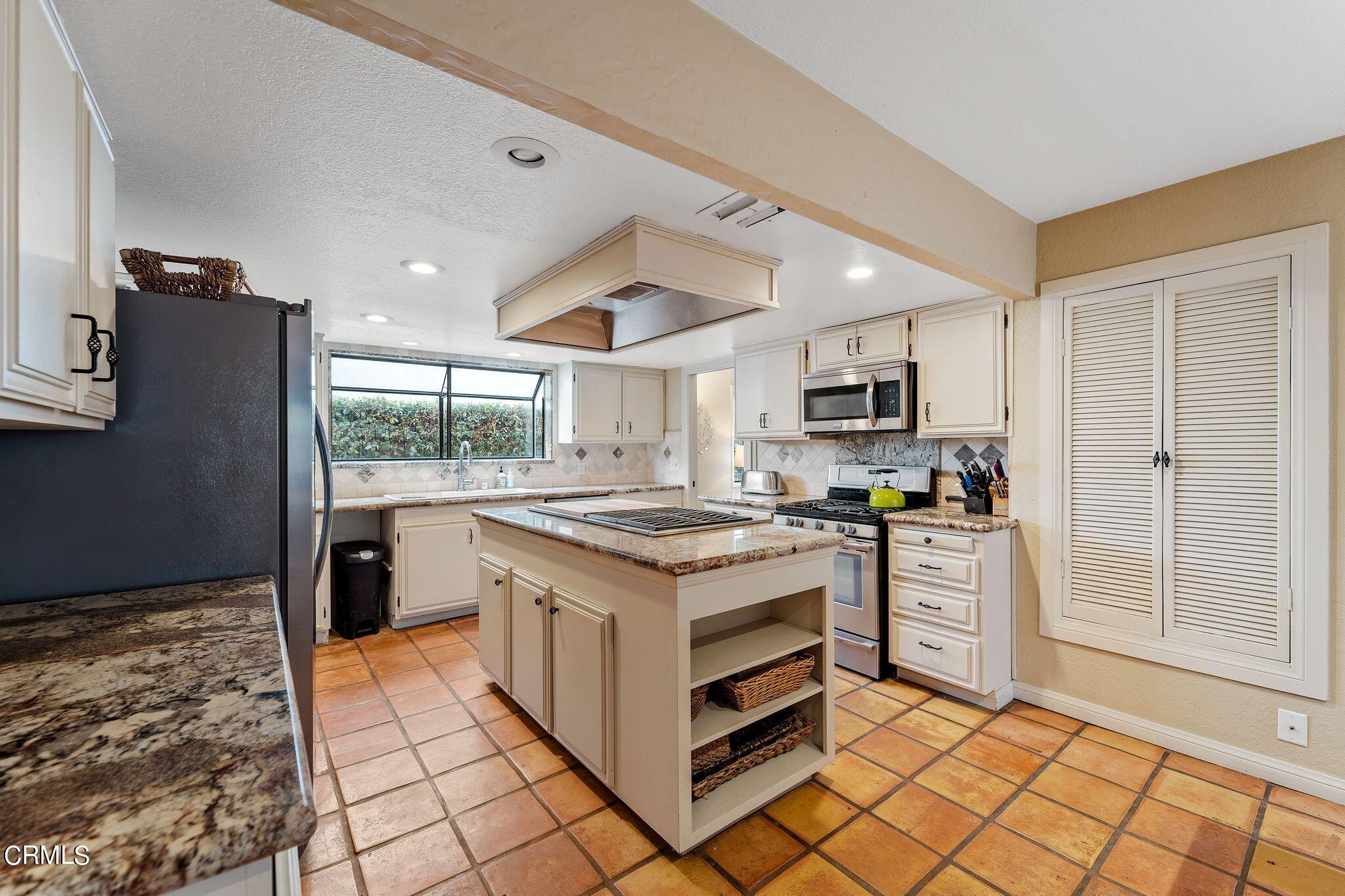 4850 Amalfi Way Oxnard, CA 93035 - Photo 9 of 51 a kitchen with stainless steel appliances granite countertop a stove top oven a sink dishwasher a refrigerator and white cabinets with wooden floor