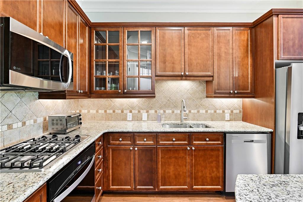 3635 East Paces Circle, Unit 1410 Atlanta, GA 30326 - Photo 18 of 68 a kitchen with granite countertop a stove top oven cabinetry a sink and a counter