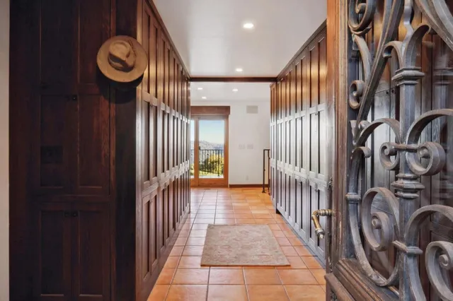 a spacious bedroom with a bed a table and potted plant with wooden floor