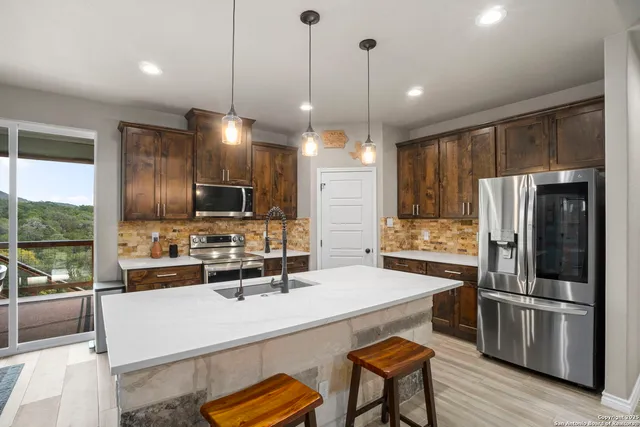 a kitchen with kitchen island a refrigerator and a stove top oven