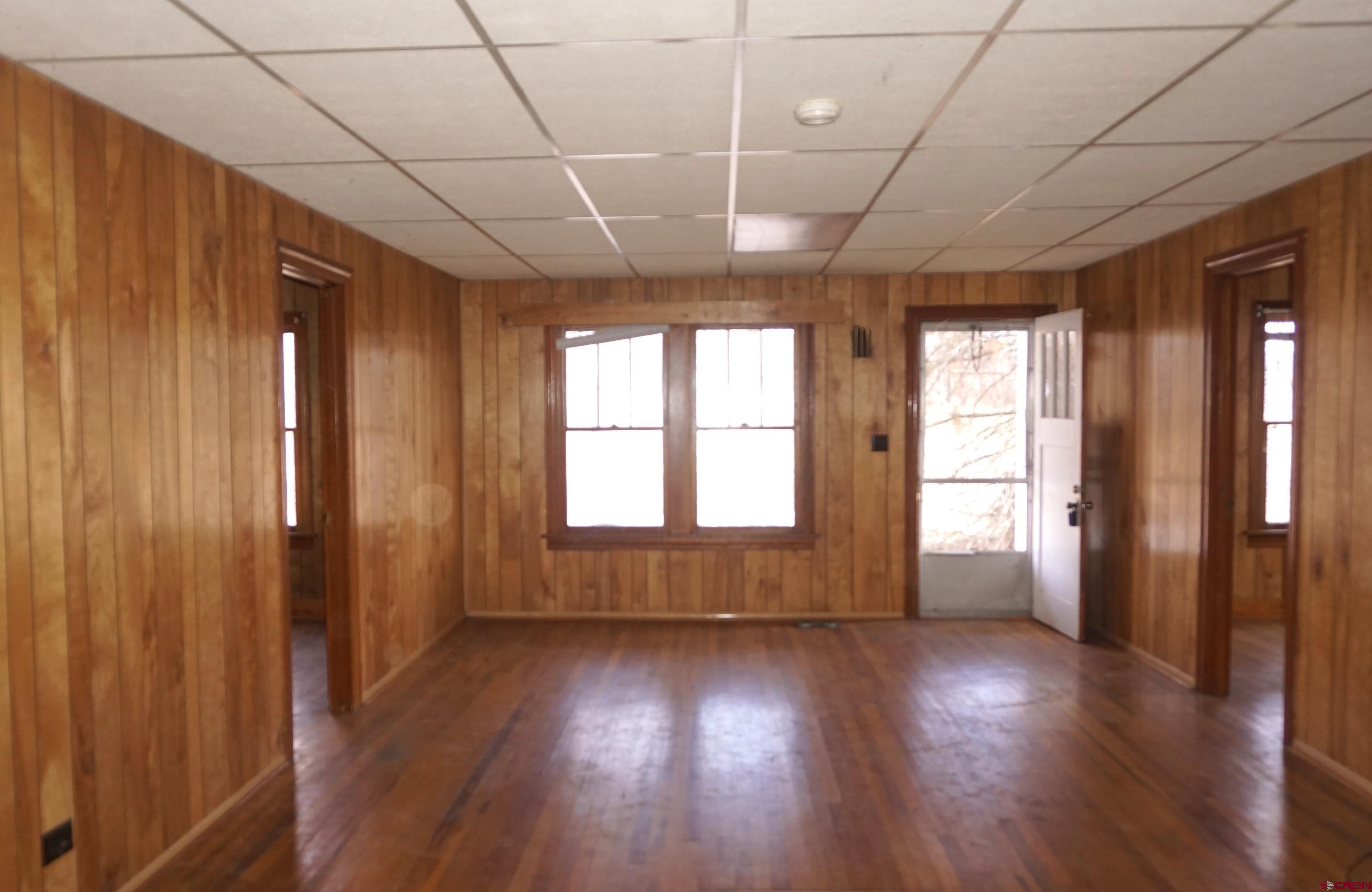 19235 2325th Road Cedaredge, CO 81413 - Photo 8 of 34 an empty room with wooden floor and windows with curtains