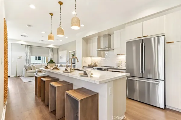 a kitchen with stainless steel appliances granite countertop a sink a stove a refrigerator and island with wooden floor