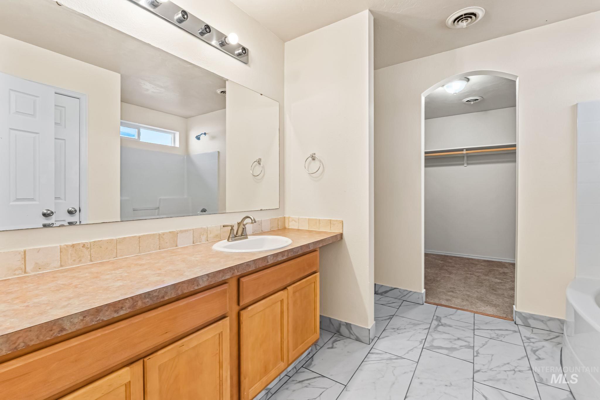 4523 Duke Street Caldwell, ID 83607 - Photo 18 of 27 Bathroom with light marble finish floors, a bathtub, a spacious closet, and vanity