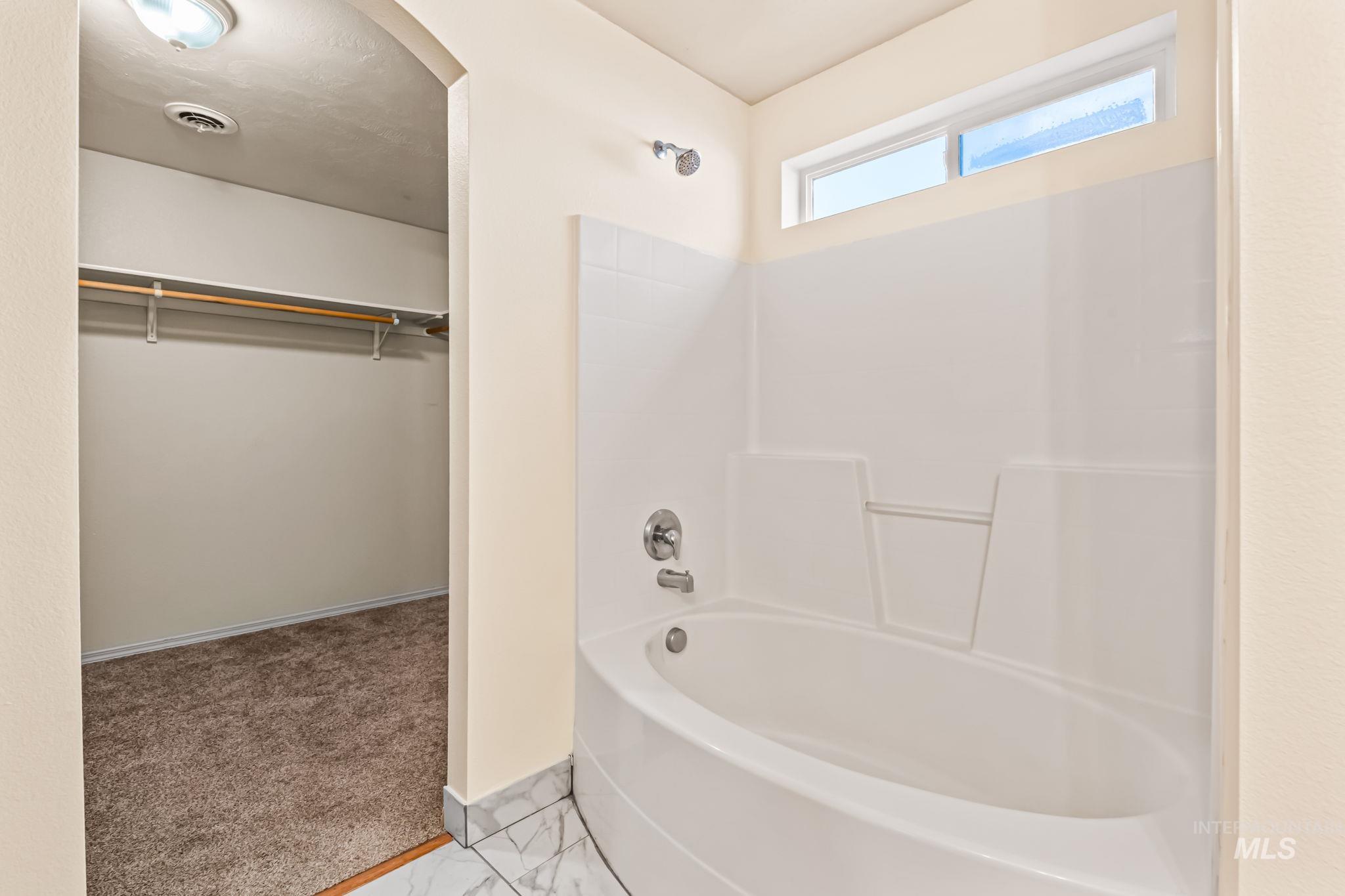 4523 Duke Street Caldwell, ID 83607 - Photo 19 of 27 Bathroom with a walk in closet, tub / shower combination, light colored carpet, and light marble finish flooring