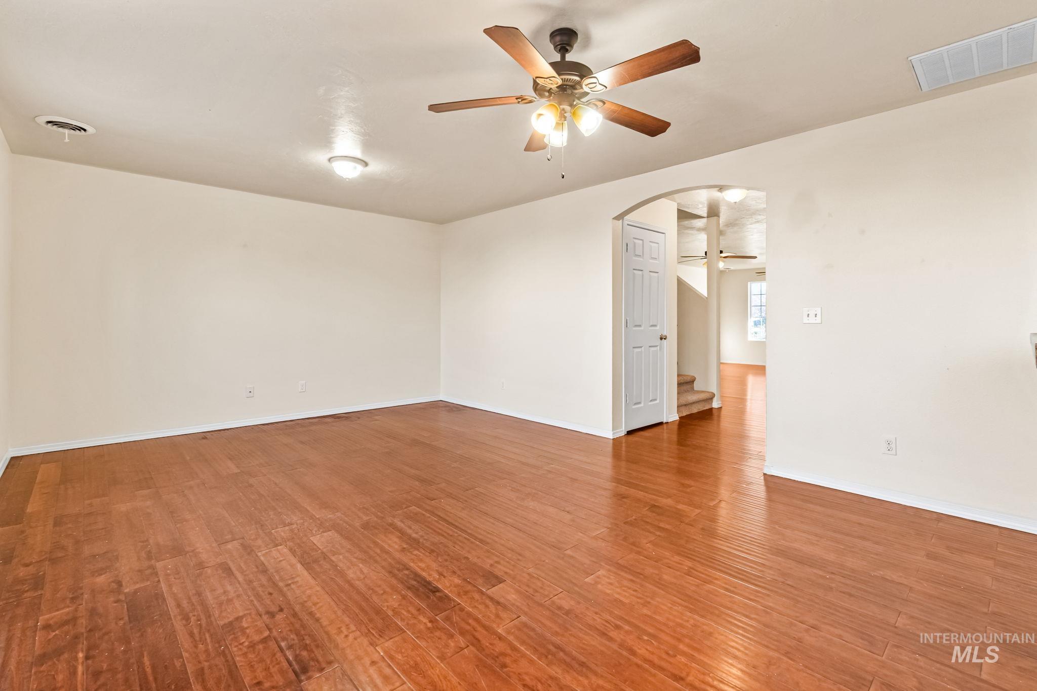 4523 Duke Street Caldwell, ID 83607 - Photo 8 of 27 Empty room featuring ceiling fan, arched walkways, and light wood finished floors