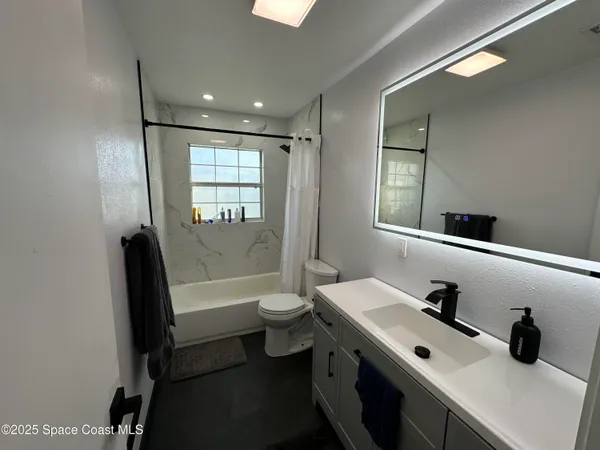 a bathroom with a double vanity sink toilet mirror and bathtub