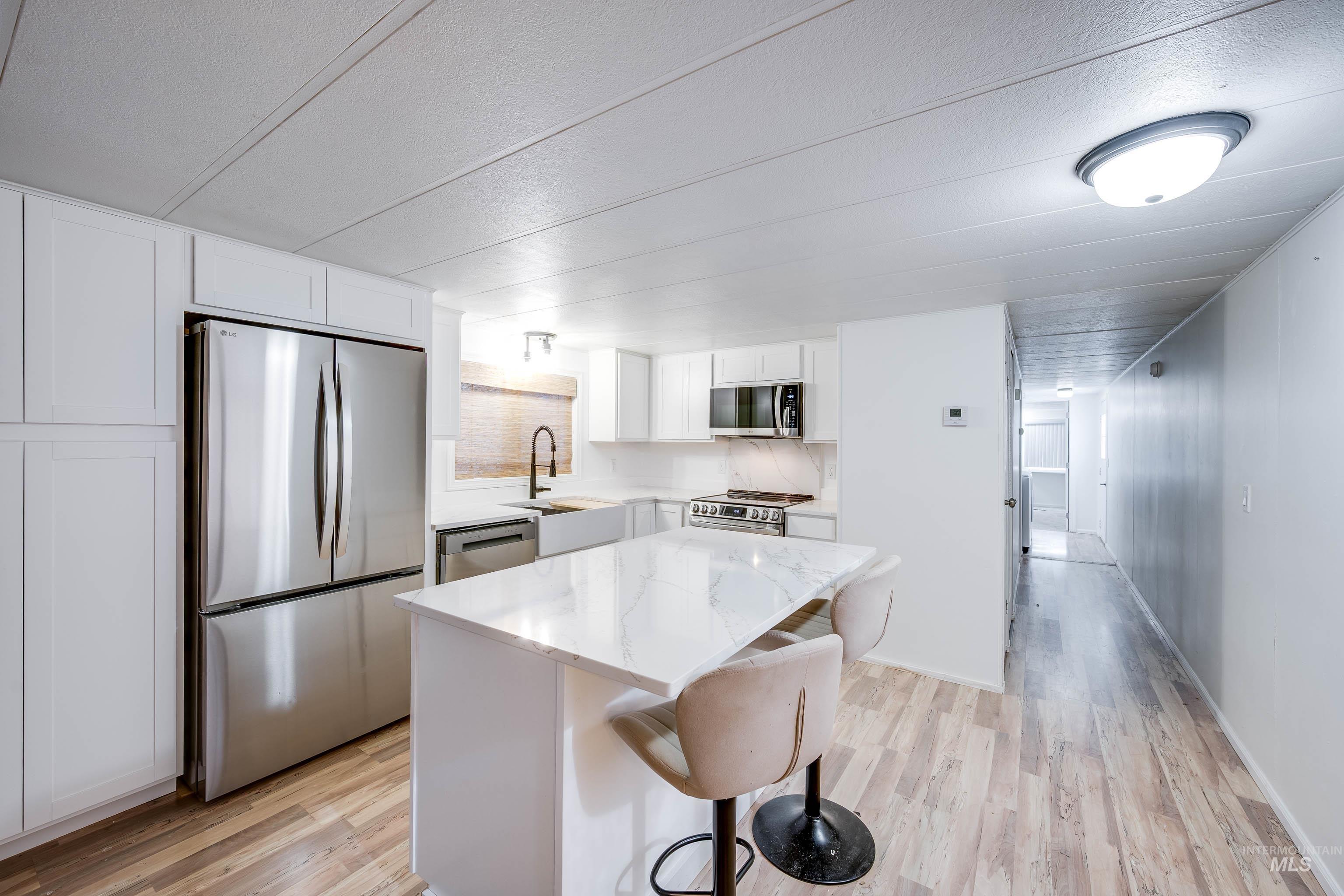 411 North Almon Street, Unit 304 Moscow, ID 83843 - Photo 10 of 21 Kitchen with white cabinets, stainless steel appliances, a kitchen breakfast bar, light wood-style flooring, and a kitchen island