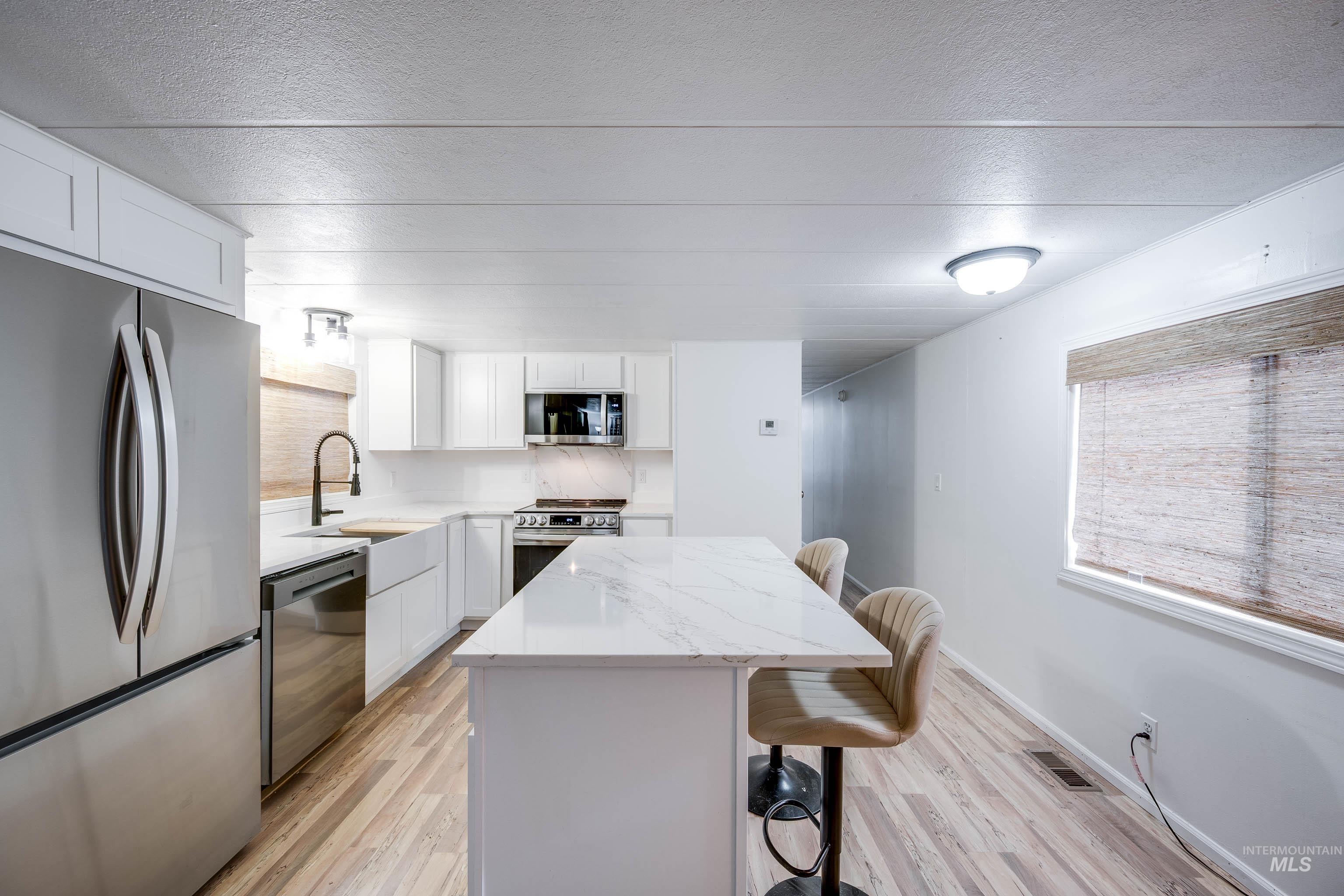 411 North Almon Street, Unit 304 Moscow, ID 83843 - Photo 8 of 21 Kitchen with a kitchen breakfast bar, stainless steel appliances, white cabinetry, light stone countertops, and a kitchen island