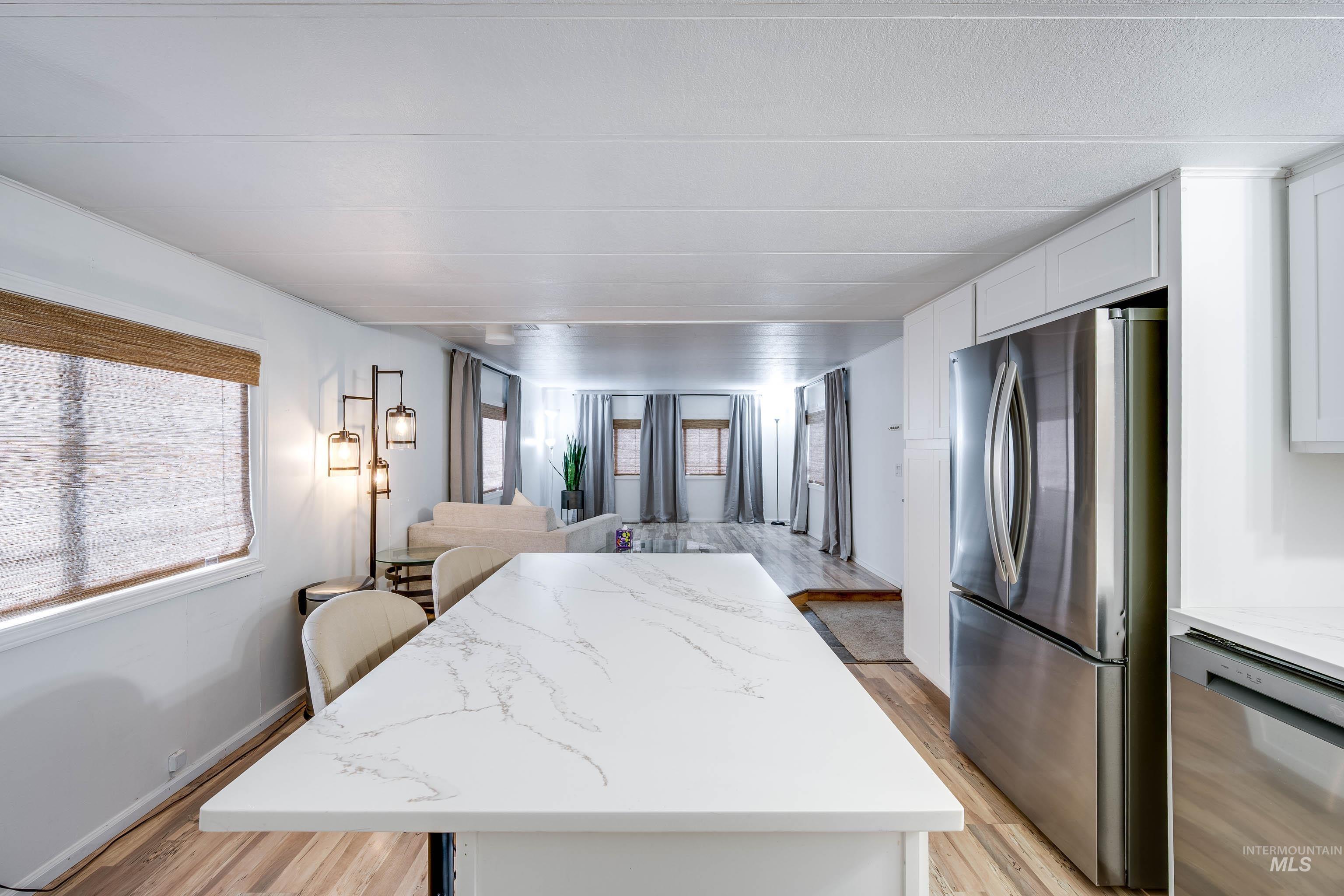 411 North Almon Street, Unit 304 Moscow, ID 83843 - Photo 20 of 21 Kitchen featuring stainless steel appliances, a center island, open floor plan, light wood-style flooring, and light stone countertops